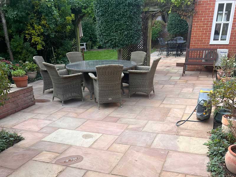 large sandstone patio blended into a traditional style garden with mature shrubs