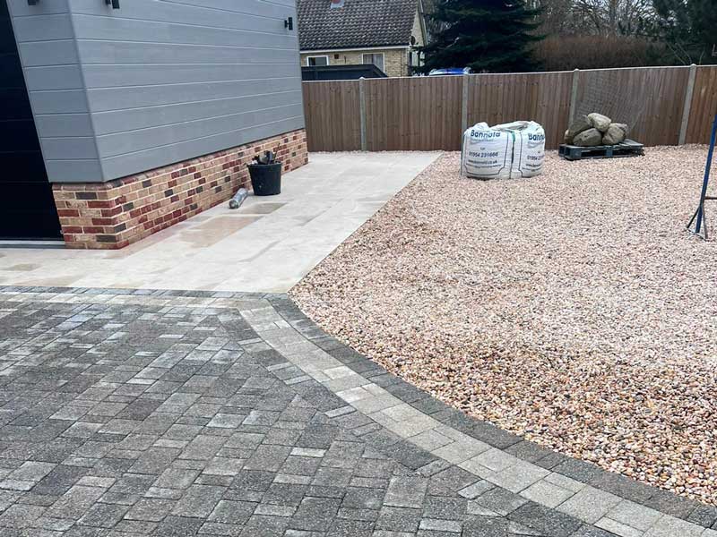 Section of a large driveway showing different materials in use - brick paving for parking, porcelain paving for walkways and gravel for ornamental areas