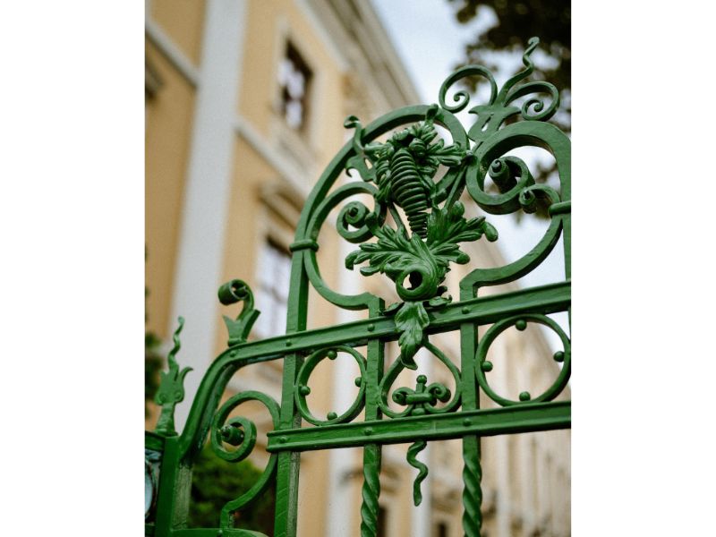 detail of an ornate metal gate painted green with lots of swirls and shapes