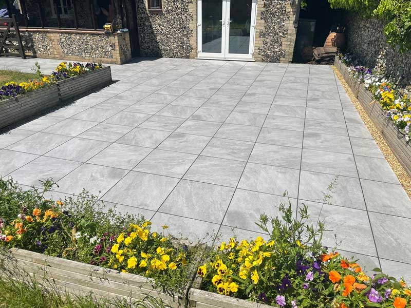 light grey porcelain patio surrounded by low rectangular planters with yellow and orange planting scheme