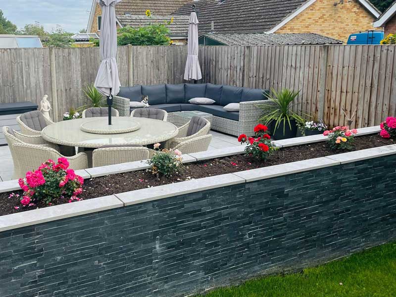 small newbuild garden with raised beds decorated by split faced wall cladding