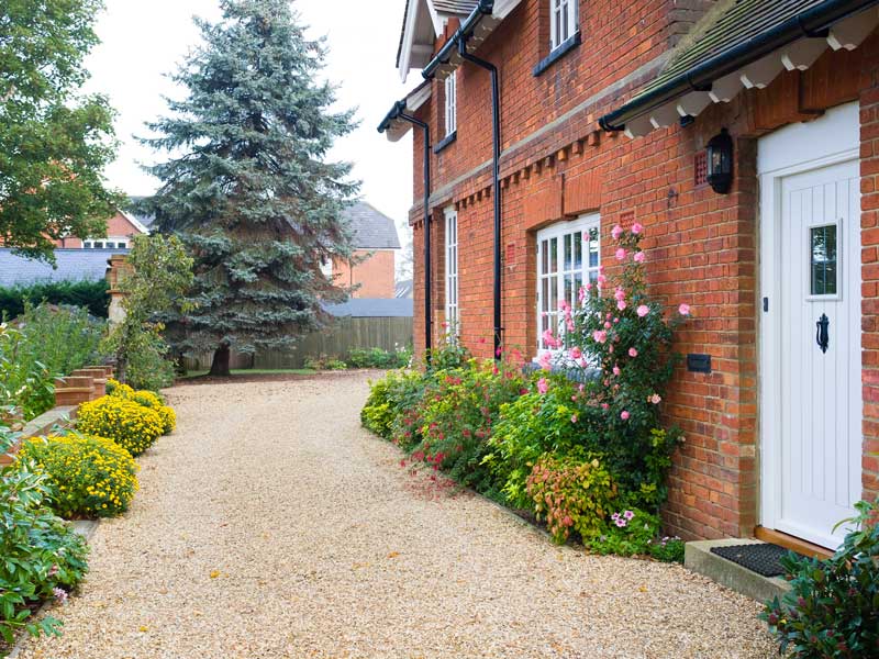 traditional gravel driveway with edwardian style property to the right of the image and lawned gardens to the left